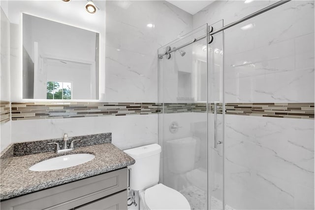 bathroom featuring vanity, tasteful backsplash, walk in shower, tile walls, and toilet