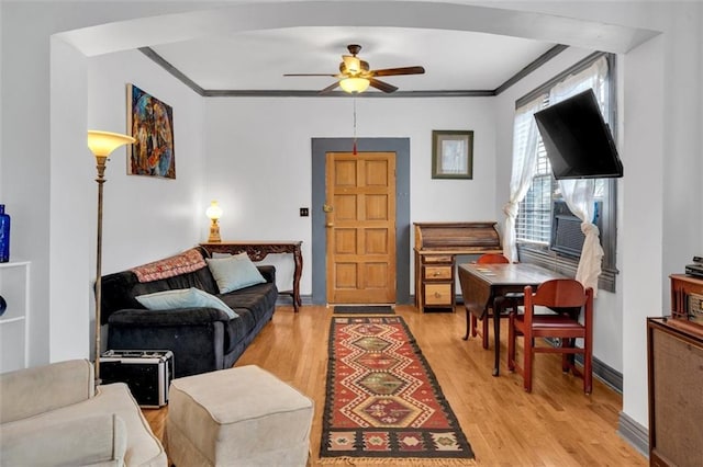 living room featuring cooling unit, ceiling fan, ornamental molding, and light wood-type flooring