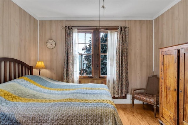 bedroom with wood-type flooring, ornamental molding, and wooden walls