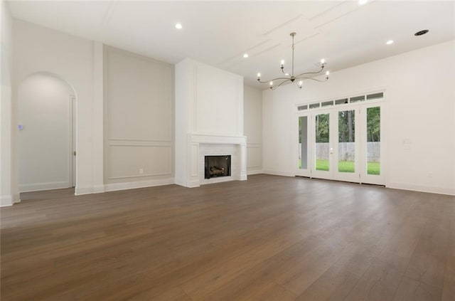 unfurnished living room featuring dark wood-type flooring, a large fireplace, and a notable chandelier