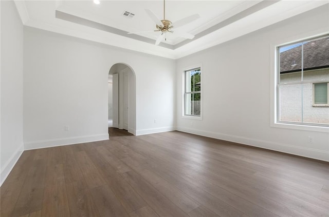 empty room with ceiling fan, dark hardwood / wood-style floors, and a raised ceiling