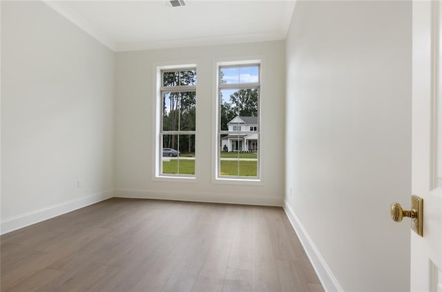 empty room featuring crown molding and hardwood / wood-style floors