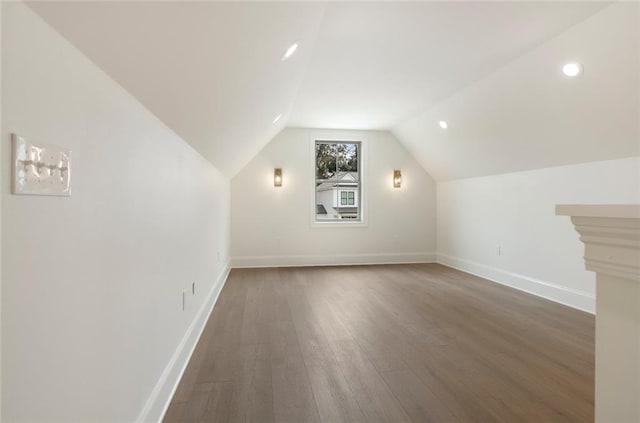 additional living space featuring vaulted ceiling and dark hardwood / wood-style flooring