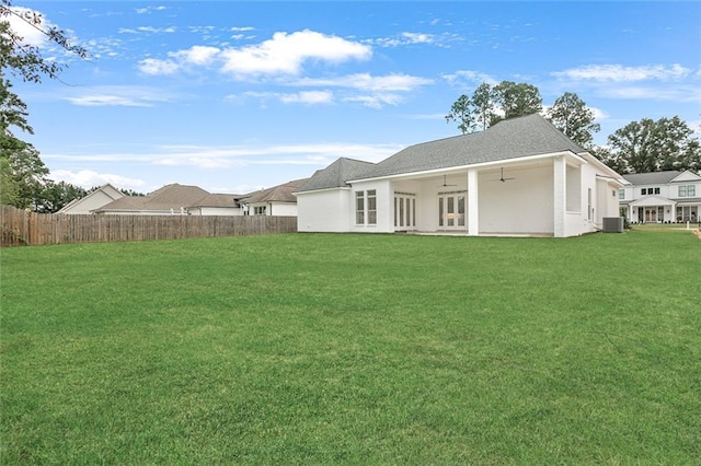 rear view of house featuring central air condition unit, a yard, and ceiling fan