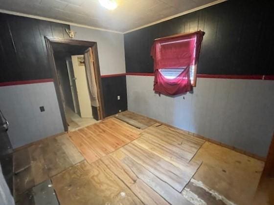 spare room featuring crown molding and wood walls