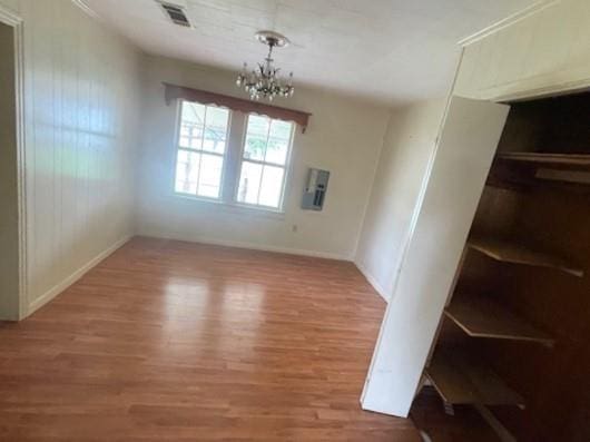 unfurnished dining area with wood-type flooring and an inviting chandelier