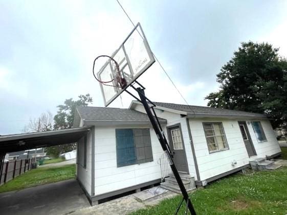 rear view of property with a carport and a lawn