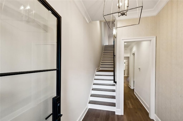 stairway with crown molding, dark hardwood / wood-style floors, and a notable chandelier