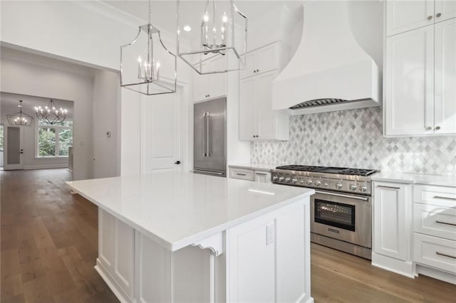 kitchen with a kitchen island, custom range hood, hardwood / wood-style floors, high end appliances, and tasteful backsplash