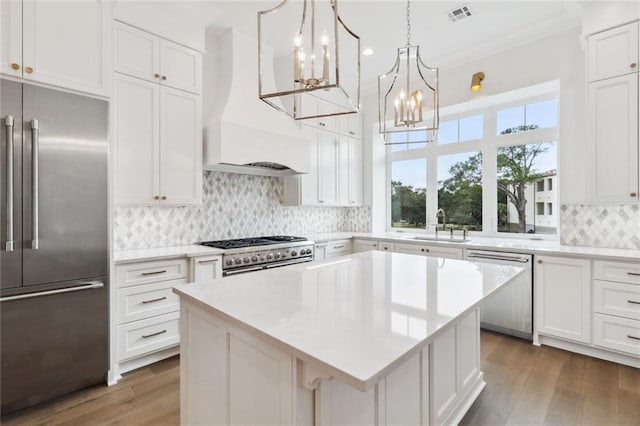 kitchen with high end appliances, tasteful backsplash, hardwood / wood-style floors, and custom exhaust hood