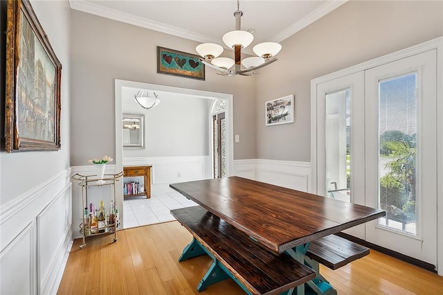 dining space with light hardwood / wood-style floors, an inviting chandelier, and ornamental molding