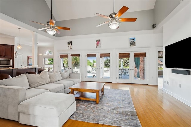 living room with french doors, light wood-type flooring, high vaulted ceiling, and ceiling fan