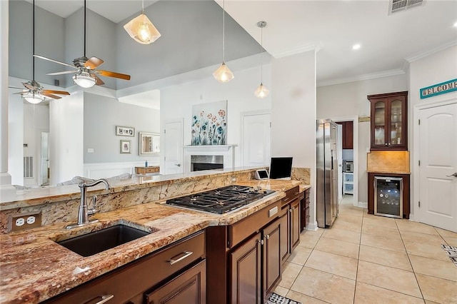 kitchen featuring appliances with stainless steel finishes, light stone counters, beverage cooler, sink, and light tile patterned floors