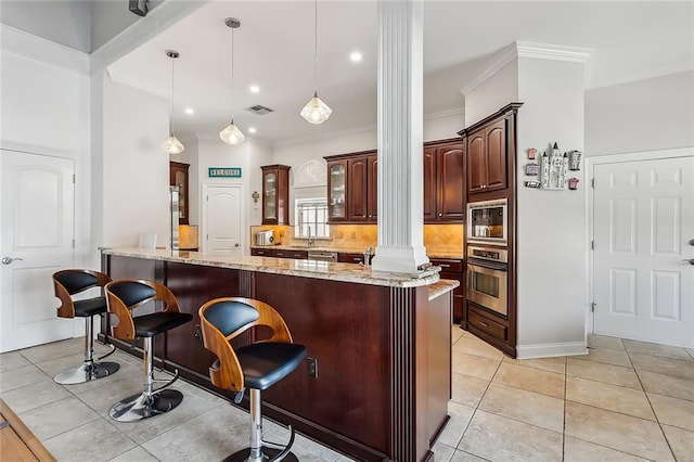 bar featuring hanging light fixtures, light stone countertops, light tile patterned floors, appliances with stainless steel finishes, and decorative columns