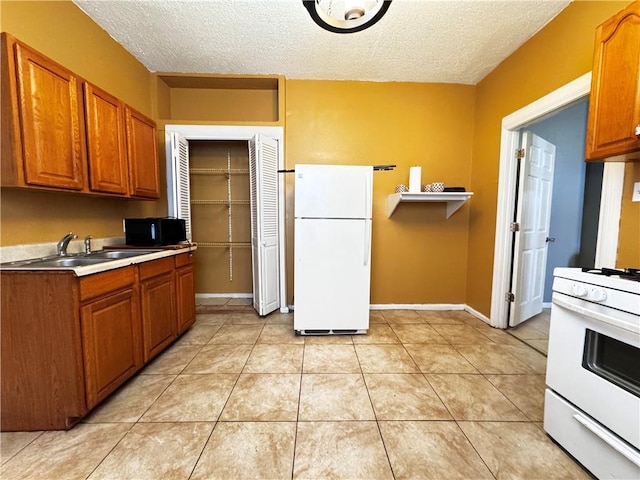 kitchen with a textured ceiling, white appliances, sink, and light tile patterned floors