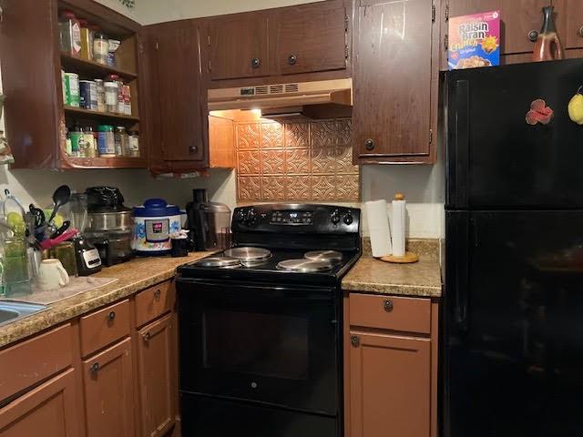 kitchen with black appliances, light stone countertops, and wall chimney exhaust hood