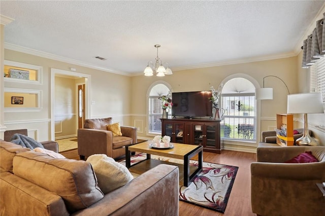 living room featuring hardwood / wood-style floors, a textured ceiling, an inviting chandelier, and ornamental molding