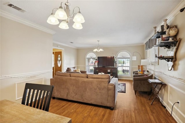 living room featuring wood-type flooring, crown molding, and a notable chandelier