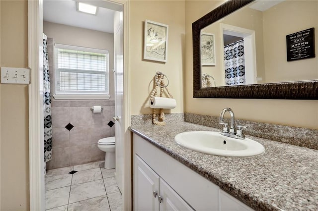 bathroom with vanity, toilet, and tile walls