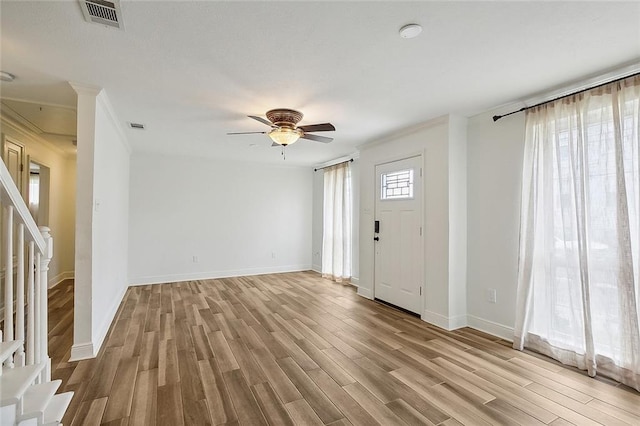 entrance foyer with a healthy amount of sunlight, ceiling fan, light wood-type flooring, and crown molding