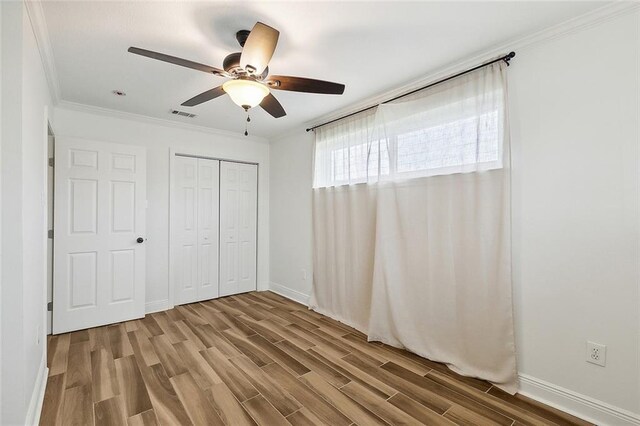 unfurnished bedroom featuring ceiling fan, hardwood / wood-style flooring, a closet, and ornamental molding