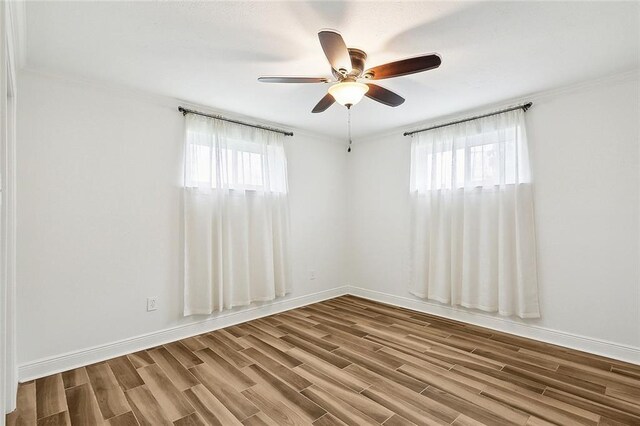 empty room featuring hardwood / wood-style flooring, ornamental molding, ceiling fan, and plenty of natural light