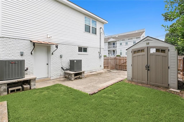 rear view of house with a storage shed, central AC, and a yard