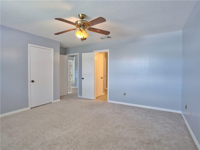 unfurnished bedroom with ceiling fan, light carpet, and a textured ceiling