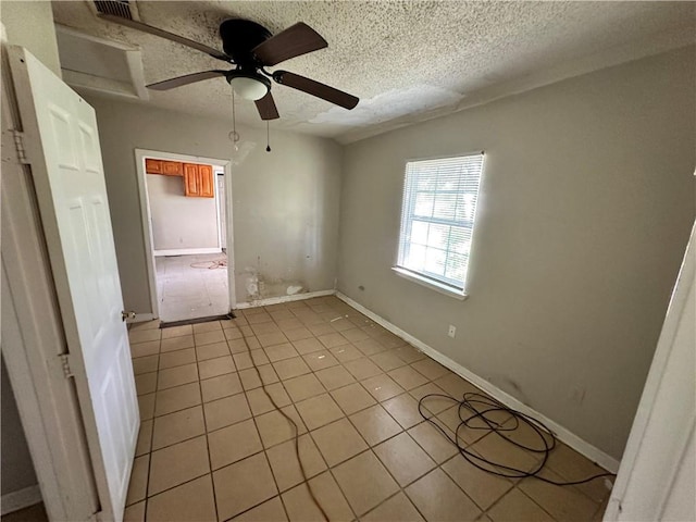 unfurnished bedroom featuring ceiling fan, light tile patterned floors, and a textured ceiling