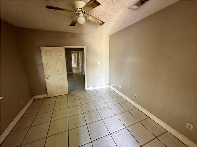 unfurnished bedroom featuring ceiling fan, light tile patterned floors, and a textured ceiling