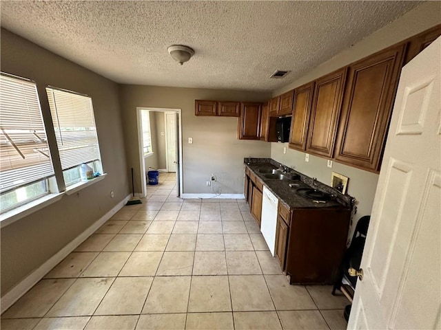 kitchen featuring a textured ceiling, sink, white dishwasher, and light tile patterned floors