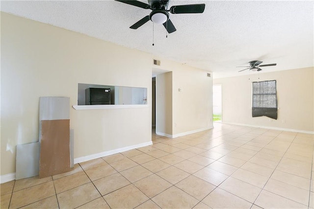 unfurnished room with ceiling fan, a textured ceiling, and light tile patterned floors