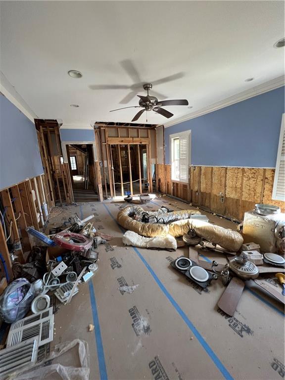 unfurnished living room featuring ornamental molding and ceiling fan