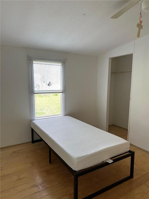 bedroom featuring ceiling fan, a closet, vaulted ceiling, and light hardwood / wood-style floors