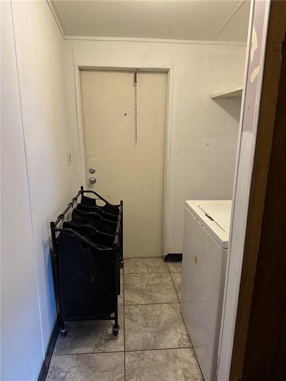 washroom with a textured ceiling, washer / dryer, and light tile patterned floors