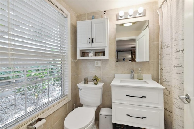 bathroom with vanity, toilet, and tile walls