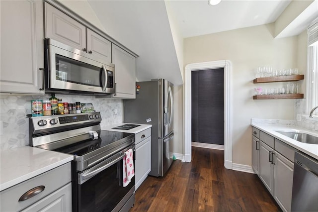 kitchen featuring stainless steel appliances, gray cabinets, sink, and backsplash