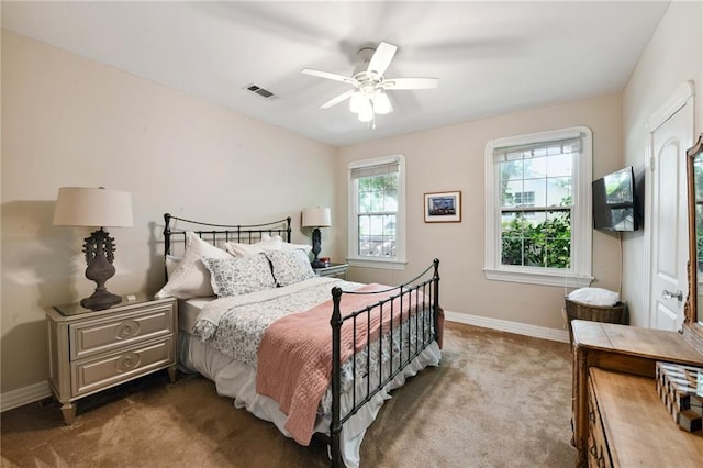 bedroom with multiple windows, ceiling fan, and dark colored carpet