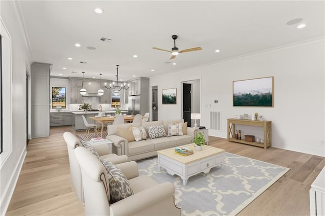 living room featuring ornamental molding, ceiling fan with notable chandelier, and light wood-type flooring