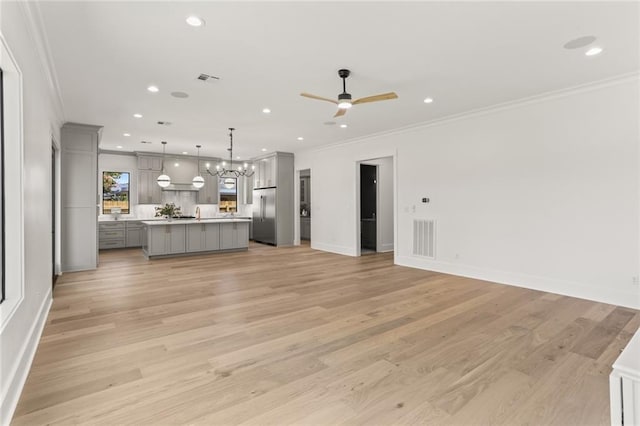 unfurnished living room with crown molding, light hardwood / wood-style flooring, and ceiling fan with notable chandelier