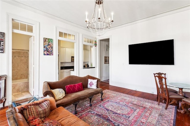 living room with wood-type flooring, ornamental molding, and a chandelier