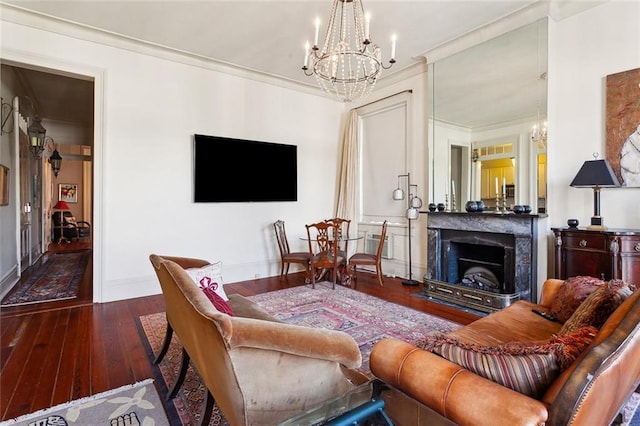 living room with dark hardwood / wood-style flooring, a notable chandelier, crown molding, and a high end fireplace