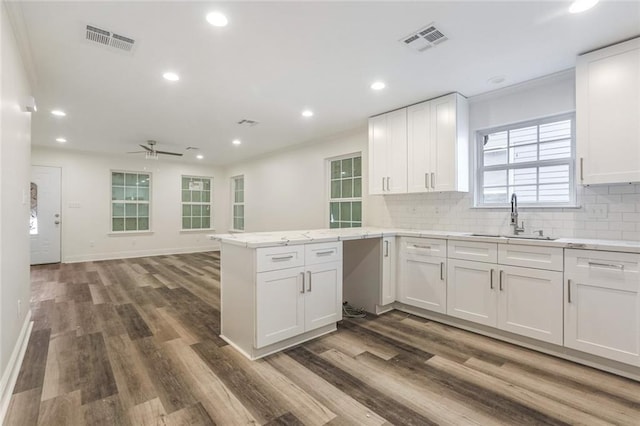 kitchen with sink, white cabinets, backsplash, kitchen peninsula, and dark wood-type flooring