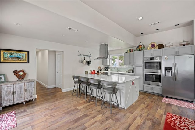 31753 River Pines Dr, Springfield, LA 70462 - kitchen with stainless steel appliances, light countertops, visible vents, island range hood, and a breakfast bar