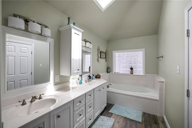 bathroom with hardwood / wood-style floors, double vanity, vaulted ceiling, and a bath