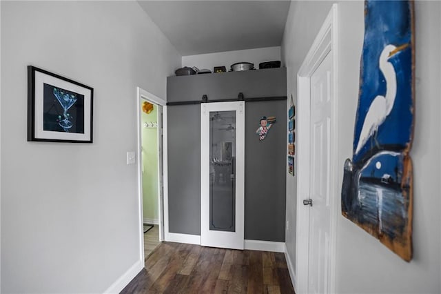 hallway with a barn door and dark hardwood / wood-style floors