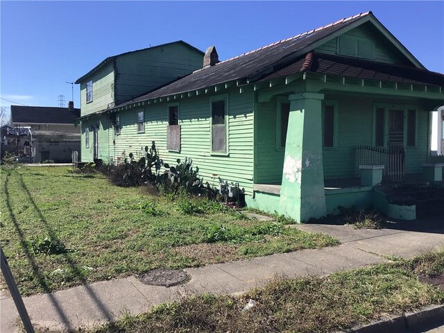 view of home's exterior featuring covered porch and a lawn