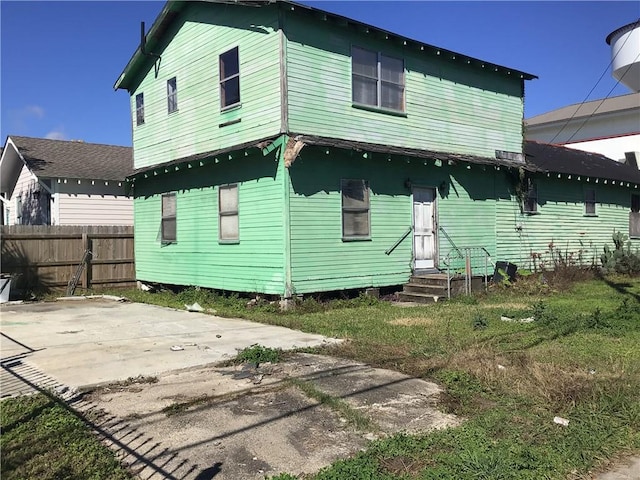 back of property with entry steps, a patio area, and fence