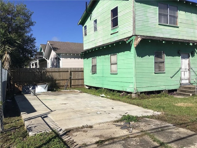 back of house with entry steps, a patio, and fence