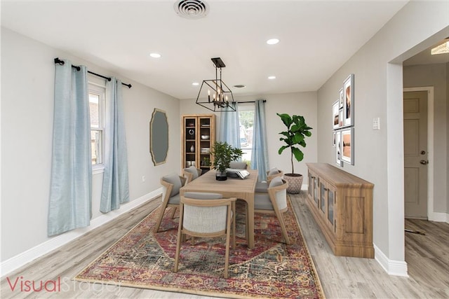 dining space with a wealth of natural light, light hardwood / wood-style floors, and a notable chandelier